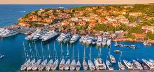 Vista aérea de la marina de Porto Cervo con yates de lujo al atardecer en la Costa Esmeralda.