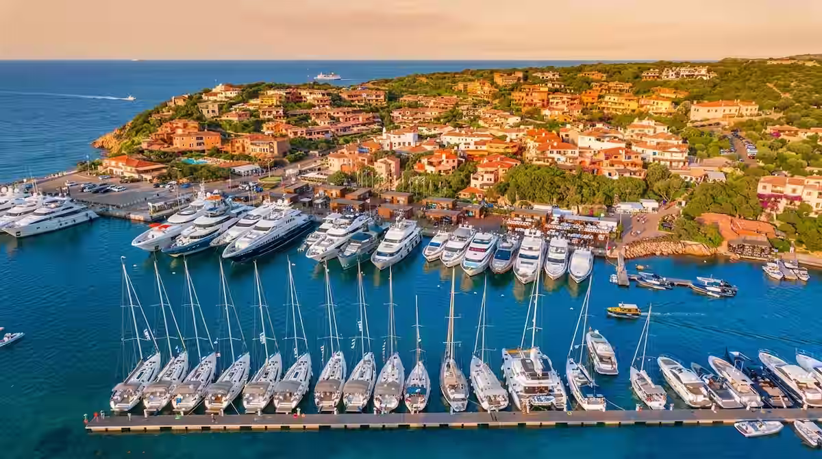 Qué ver en la Costa Esmeralda de Cerdeña: De Porto Cervo a sus playas encantadoras 1 Vista aérea de la marina de Porto Cervo con yates de lujo al atardecer en la Costa Esmeralda.